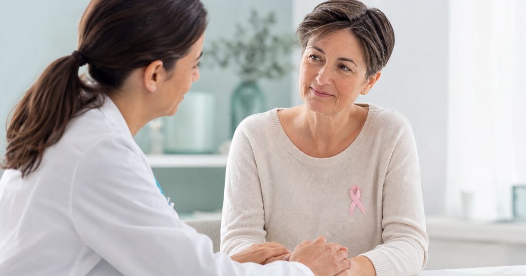 Médica acompañando a una paciente oncológica que lleva un lazo rosa