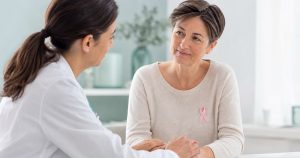 Médica acompañando a una paciente oncológica que lleva un lazo rosa
