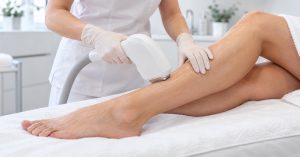 Profesional realizando un tratamiento de depilación láser en la pierna de una mujer